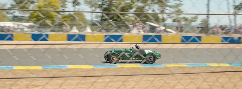 A green race car is driving on the track.