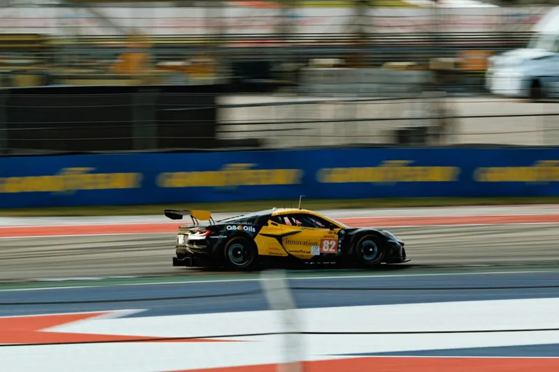 A yellow race car driving down a race track